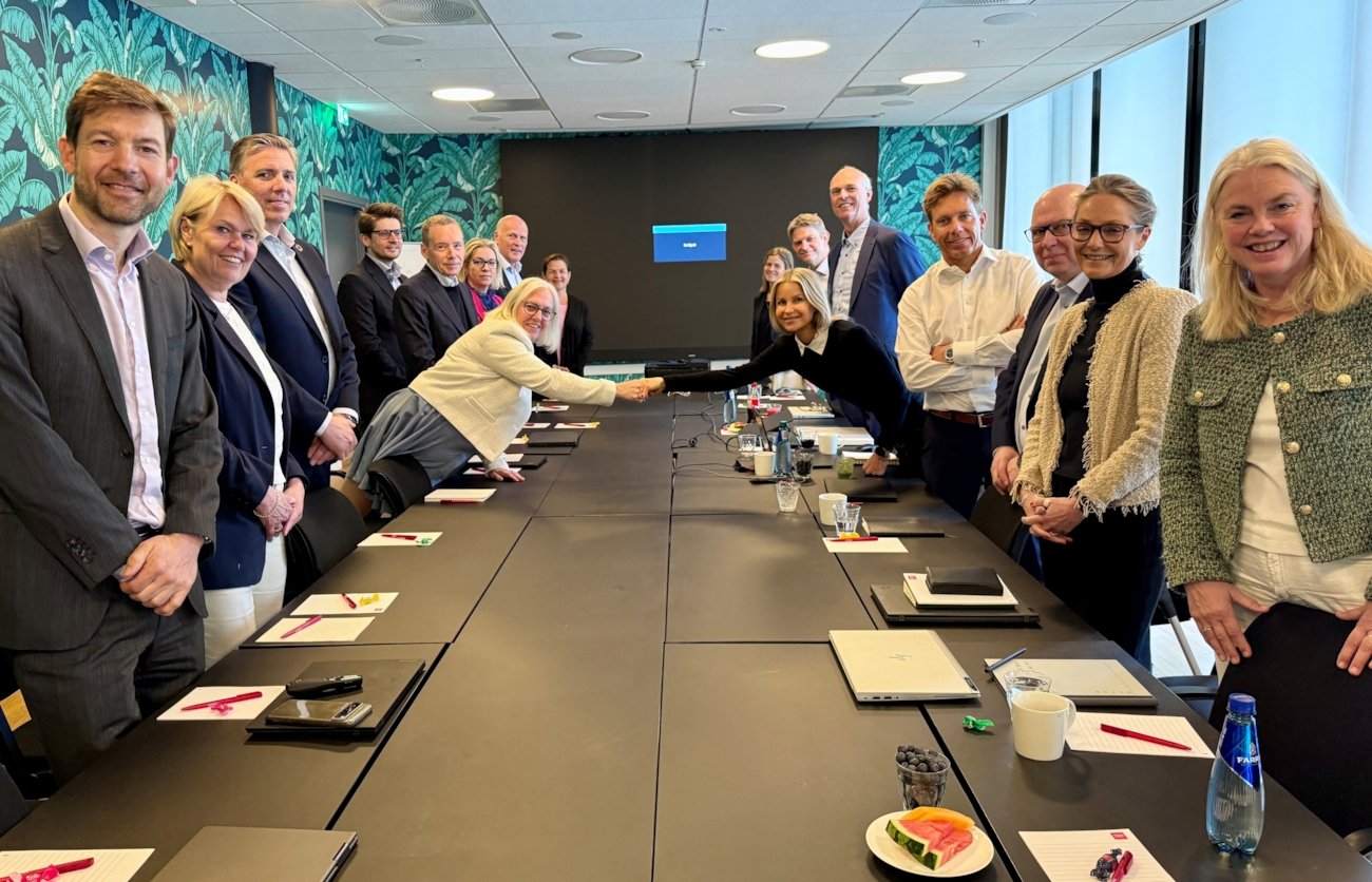 Finansforbundets og Finans Norges representanter samlet rundt forhandlingsbordet og forhandlingslederne hilser over bordet. Foto.