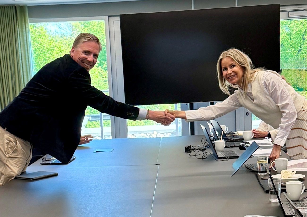 De to forhandlingslederne trykker hender.Foto.