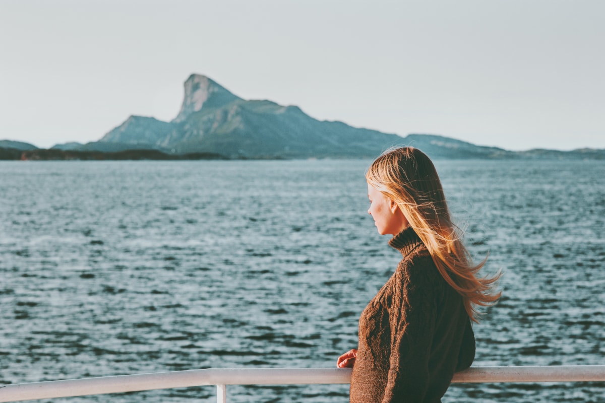 Kvinne ser utover havet. Foto.