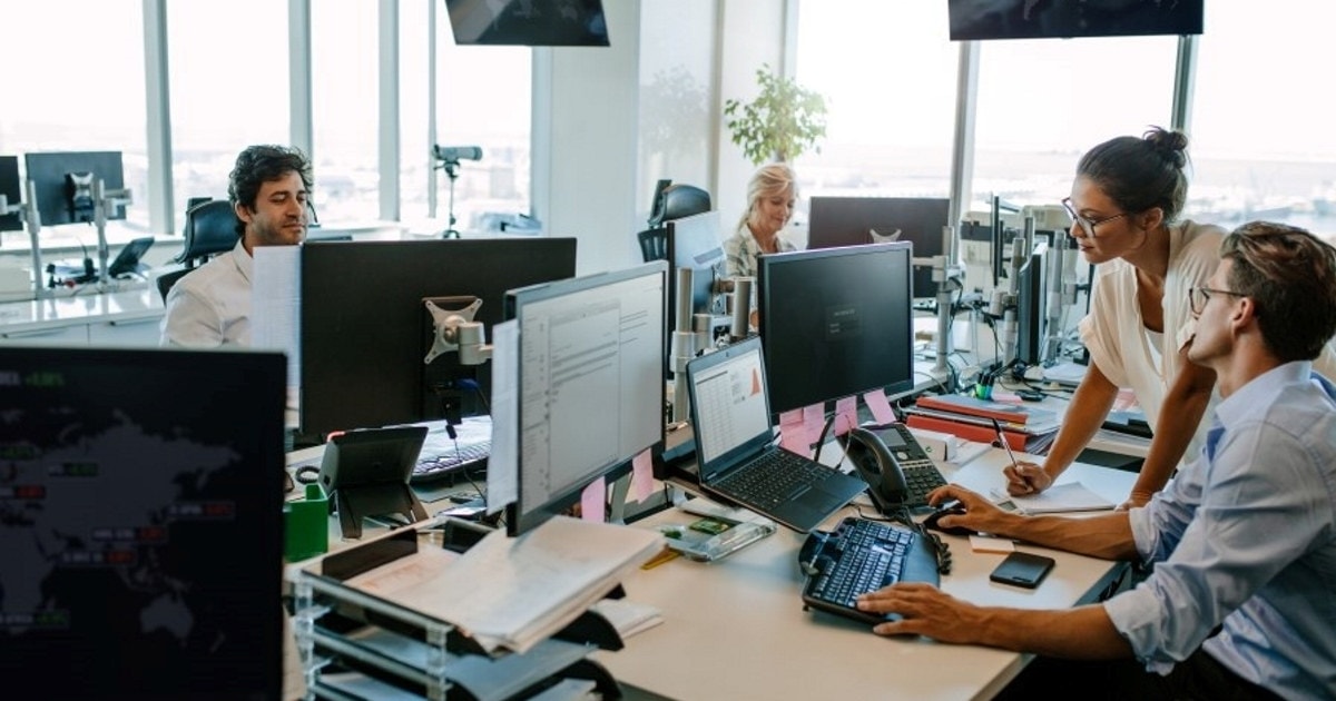 Personer som samarbeider på kontor foran pc-skjermer. Foto.