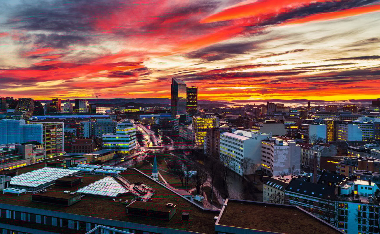 Utsikt over Oslo og ut mot Oslofjorden. Himmelen er farget i rødt ved skumring. Foto.