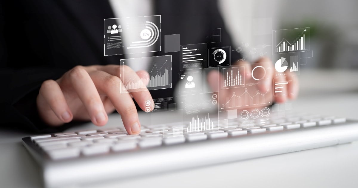 Nærbilde av hender som skriver på et tastatur. Over tastaturet vises digitale grafer, diagrammer og statistikkvisualiseringer som illustrerer analyse av data, innsikt og digitale verktøy. Foto.